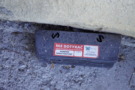 Black plastic rodent bait station placed against a concrete wall for pest control management