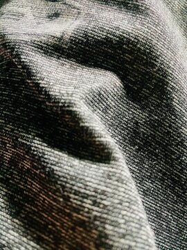 Macro Shot of Textured Grey Woven Fabric with Folds and Shadows Creating a Dynamic Pattern Background