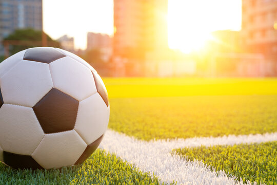 Soccer ball resting on football field at sunset
