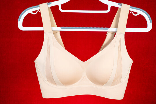 Beige seamless bra hanging on white clothes hanger