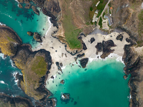 Aerial landscape directly above  Kynance Cove beach in Cornwall, UK with beach and calm ocean