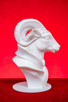 White 3D printed ram head bust sculpture against solid red background