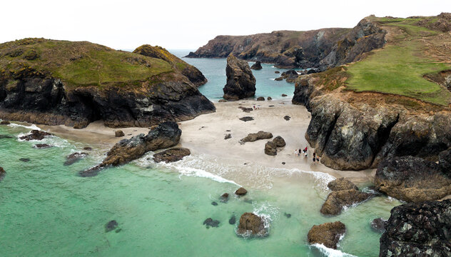 Aerial landscape of people trapped by a high tide on Kynance Cove beach in Cornwall, UK