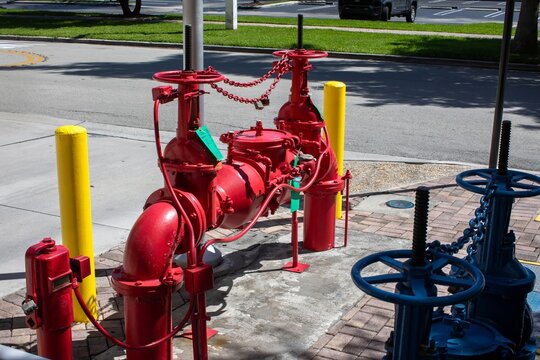 Red double check detector backflow preventer valve system for commercial building fire protection on a sidewalk