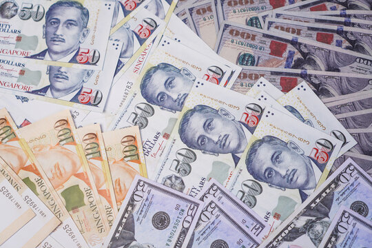 A scattered multi currency background featuring a mixture of Singapore dollar and United States dollar banknotes.