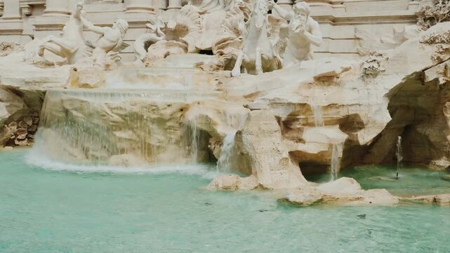 A grand trevi fountain in rome, italy with its statues and flowing water captured in cinematic slow motion footage.
