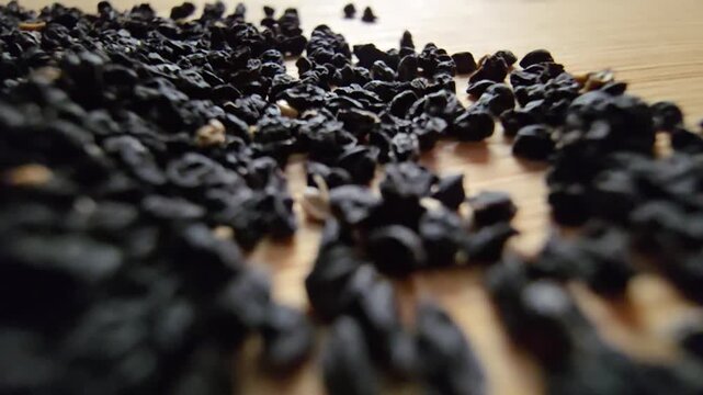 Macro video of organic leek seeds scattered on a wooden surface, showcasing agricultural harvesting, gardening concepts, and healthy plant-based ingredients in a natural setting.   