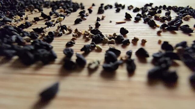 Macro close-up video of organic leek seeds scattered across a wooden surface, highlighting agricultural harvesting, gardening concepts, and healthy plant-based ingredients in a natural setting.   