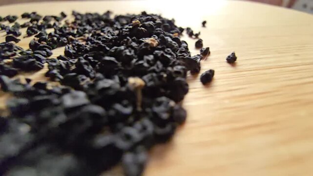 Macro close-up video of organic leek seeds scattered across a wooden surface, highlighting agricultural harvesting, gardening concepts, and healthy plant-based ingredients in a natural setting.   