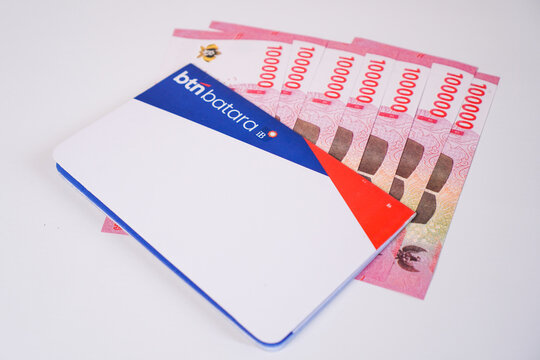 Makassar, Indonesia, September 20, A BTN Batara iB sharia savings book placed diagonally over a neatly fanned-out stack of Indonesian 100.000 rupiah banknotes.