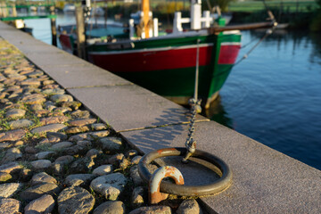 Obraz premium Close-up of mooring ring on stone quay with historic wooden ship