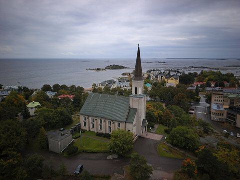 Aerial view of Hanko Church with high spire against coastal landscape and sea