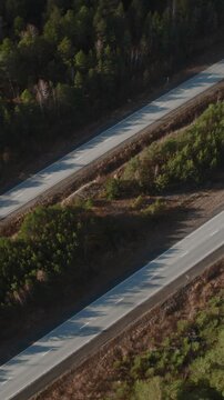 Top-down drone footage of a paved highway cutting through dense pine forest with a truck driving along the road in the Ural Mountains, Russia, daytime travel scene