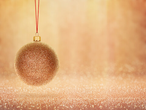 Golden glitter Christmas bauble hanging on a shimmering warm festive background. Elegant holiday decoration with sparkling bokeh lights, perfect for seasonal celebration designs