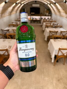Mallorca, spain, septiembre 18, 2026 hand holding tanqueray 0.0 percent non alcoholic gin bottle inside a restaurant in calvia, balearic islands, spain