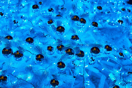 Christmas tree branches decorated with shiny baubles and glowing blue lights