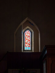 27th September 2026, Embleton, Cumbria. A striking stained glass window with a floral motif illuminates the dark interior of Saint Cuthberts Church, creating a serene and spiritual atmosphere. © Ray