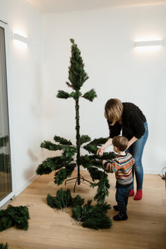 A woman and her son are making a Christmas tree at home