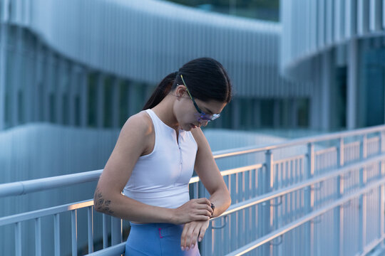Tired female athlete checks heart rate monitor on wrist after training