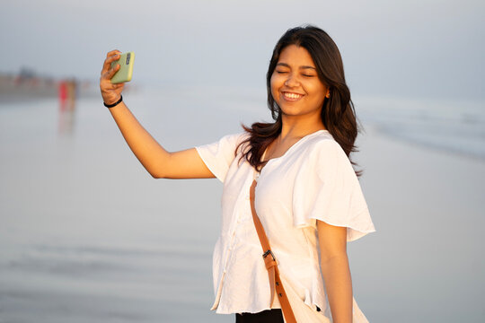 Young Indian lady filming herself in a sea beach and enjoying holiday