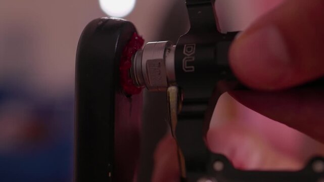 hand applying glue to a small object in a focused indoor setting with red skin tone and clean background for crafting projects and assembly tasks in a workshop or home environment.