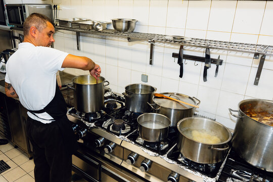 Chef Cooking with Large Pots in Restaurant Kitchen