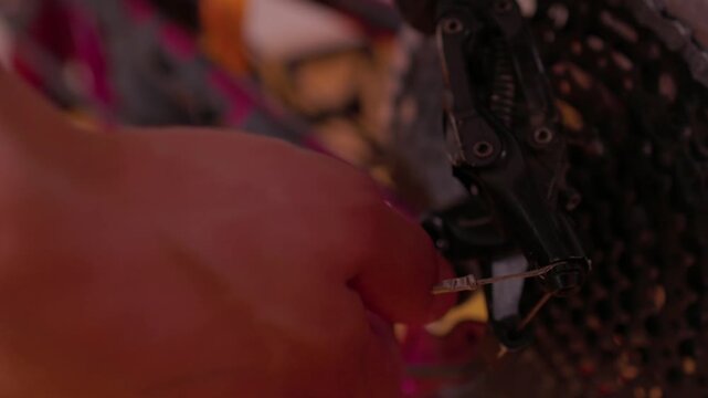 hands adjusting bicycle seat post clamp in indoor workshop setting with red and black components focused and practical close-up perspective on metallic and plastic materials.
