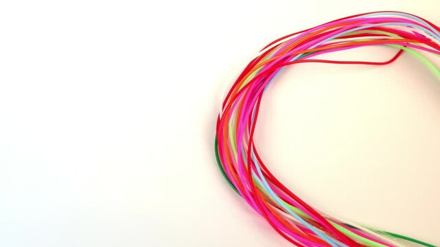 Skein of multicolored plastic strands, on a white background.