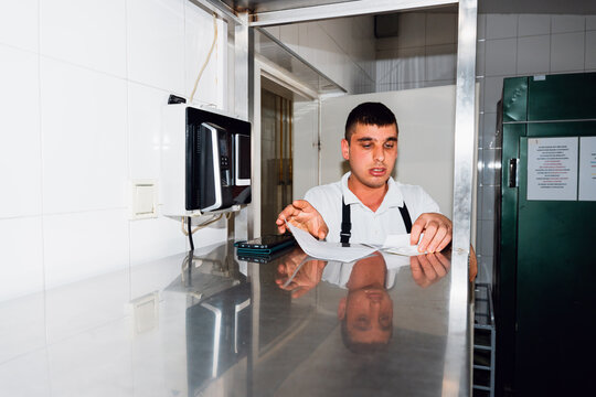 Restaurant Worker Completing Kitchen Paperwork