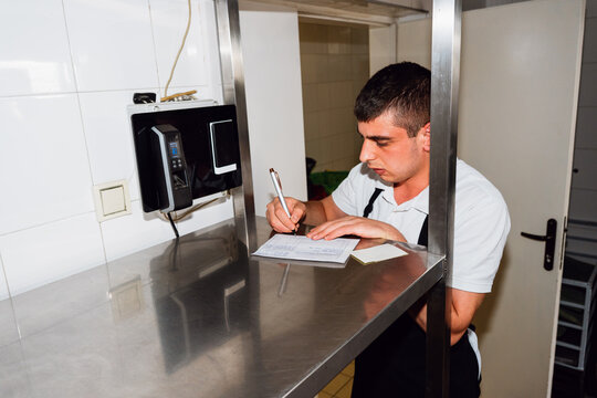 Restaurant Worker Completing Kitchen Paperwork