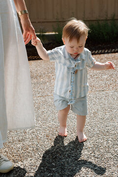 Grandmother helping toddler take first steps outdoors, candid mo