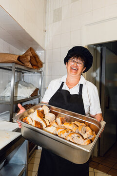 Kitchen worker holds a tray of sliced bread