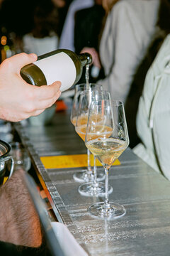Pouring a glass of white wine from a bottle mock up. Wine glasses