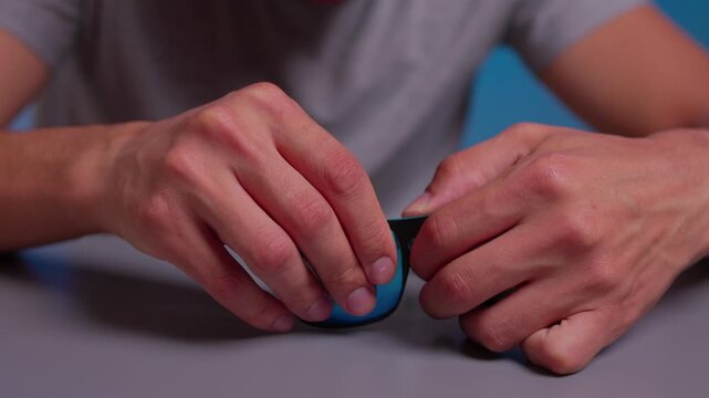 man cleaning sunglasses with a cloth against blue background in neutral mood frontal view for personal care and daily life scenes with fabric and plastic materials.