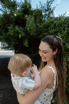 Candid mother holding baby outdoors, smiling and showing affecti