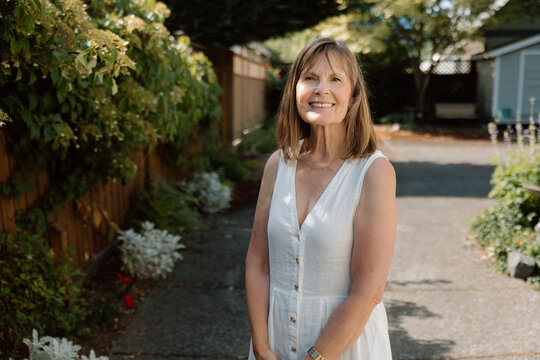 Smiling mature woman portrait in garden wearing white dress