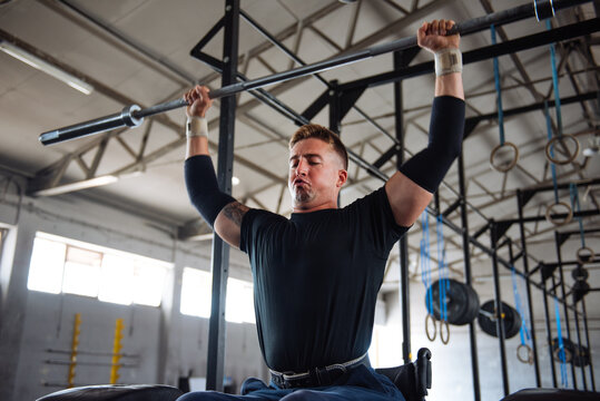 Wheelchair Athlete Lifting Barbell Overhead in Gym