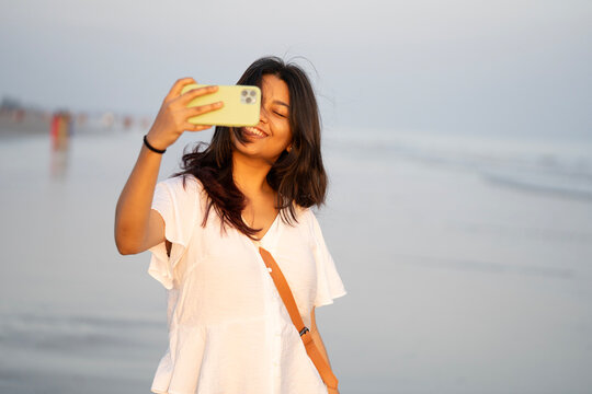 Young Indian lady filming herself in a sea beach and enjoying holiday