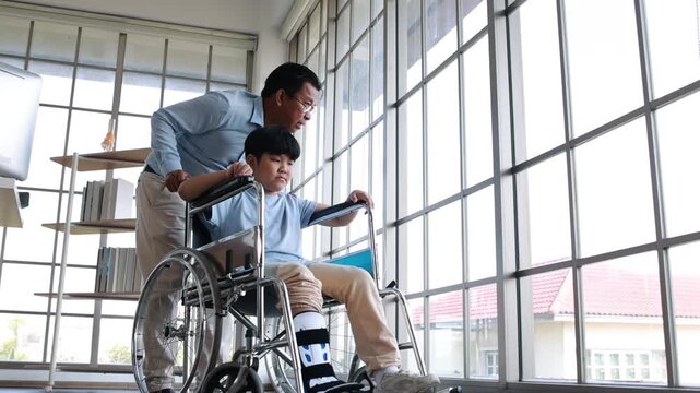 orthopedic walking, Crutches Walks Confidently. Child Step in Rehabilitation with Leg Brace. Asian father helping to support his son, who has a broken ankle