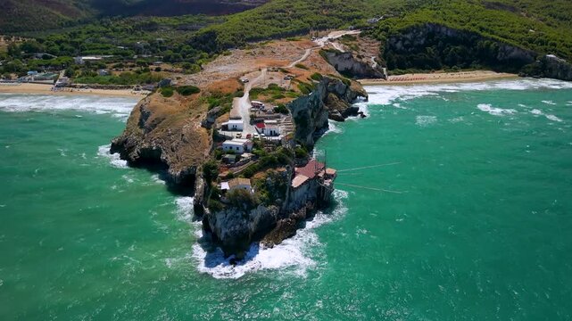 Trabucco da Elia Peschici Gargano Puglia Italy Aerial Drone High Angle Rocky Cape Seafood Restaurant Cliff Perched Crashing Waves Natural Audio B Roll 4K Video. authentic dining, italian hidden gems