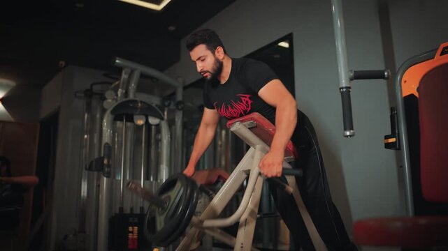 Muscular male athlete pulling handles on a chest-supported T-bar row machine focusing on heavy back strength training and workout execution.
