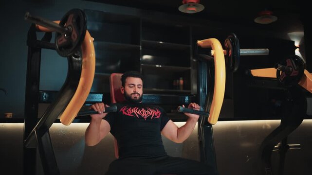 Focused young man executing seated plate-loaded incline chest press for upper body strength and muscle conditioning in a commercial gym.