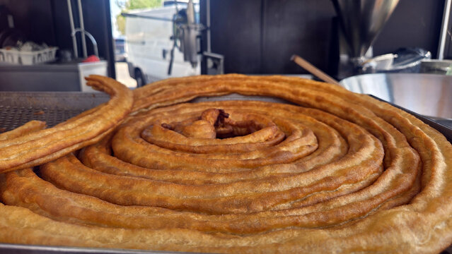 Coiled spanish porras on a hot griddle fresh from frying for bakery menu banner and food background
