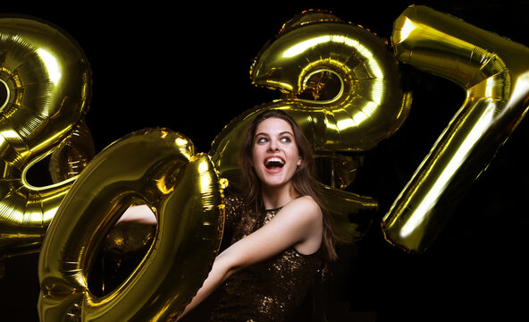 Happy gorgeous girl in stylish sexy party dress holding gold 2027 balloons, having fun at New Year's Eve Party.
