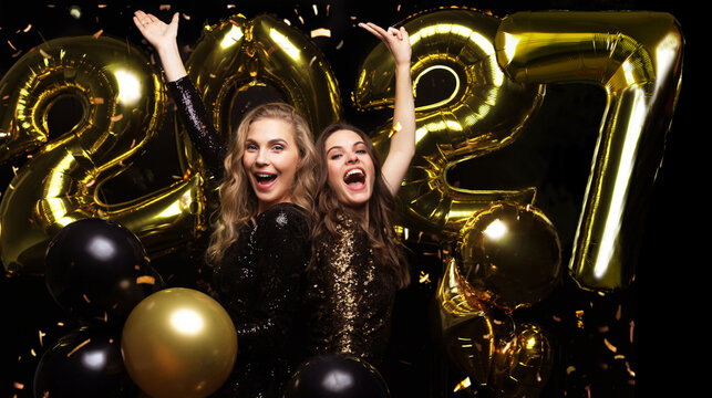 Happy gorgeous girls in stylish sexy party dresses holding gold 2027 balloons, having fun at New Year's Eve Party.