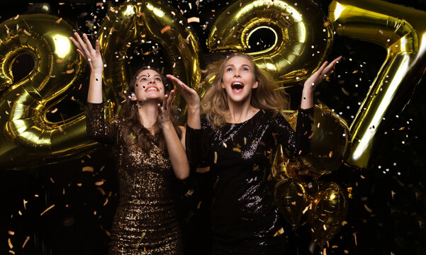 Happy gorgeous girls in stylish sexy party dresses holding gold 2027 balloons, having fun at New Year's Eve Party.