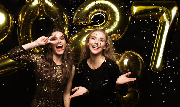 Happy gorgeous girls in stylish sexy party dresses holding gold 2027 balloons, having fun at New Year's Eve Party.