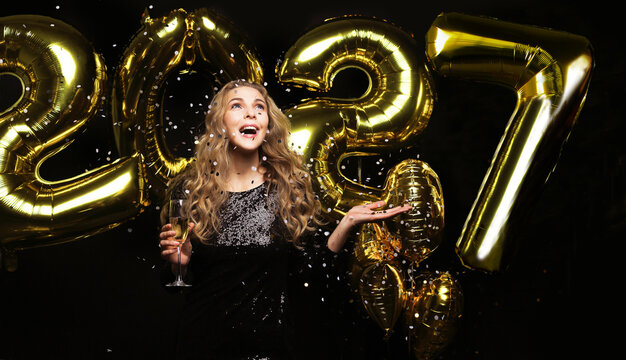 Happy gorgeous girl in stylish sexy party dress holding gold 2027 balloons, having fun at New Year's Eve Party.