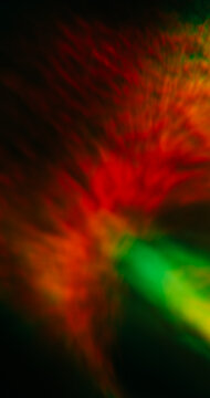 Blur light flash. Crystal lens flare. Multicolor orange green kaleidoscope on abstract dark black art background with bokeh effect.
