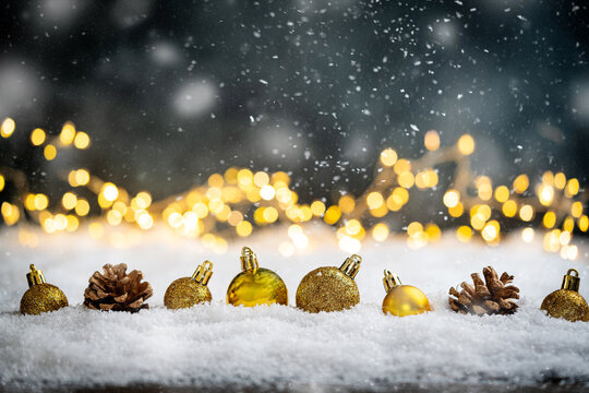 Christmas Holiday background with snow, fir tree and decorations with christmas light behind. Christmas golden balls on a winter festive background.